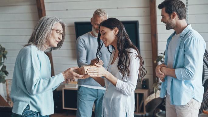 Happy senior parents meeting young couple inside the house
