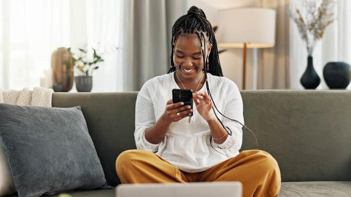 Happy, black woman with credit card and phone on sofa online shopping