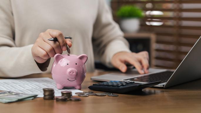 Using laptop and saving with piggy bank