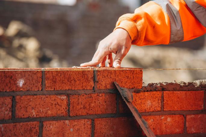 bricklayer laying bricks on construction site