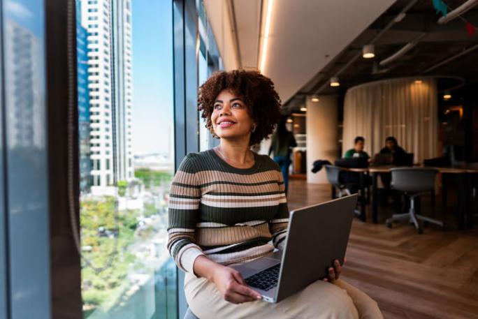 business woman in the office using laptop and looking out the window