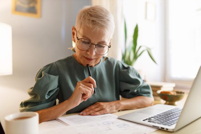 businesswoman examining papers in front of laptop
