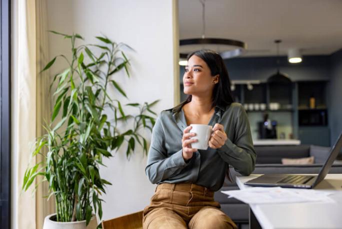 businesswoman in the office holding a mug and thinking