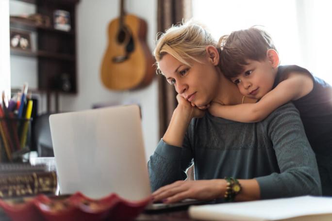 child hugging mum as she works
