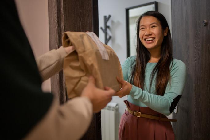 courier delivering food order to smiling customer