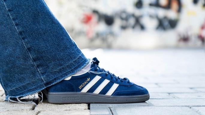 denim trouser leg and blue adidas trainer