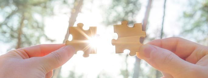 Two hands holding jigsaw pieces