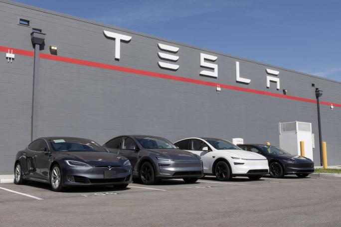 four tesla vehicles outside a tesla branded building