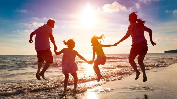 Happy family jumping together on the beach