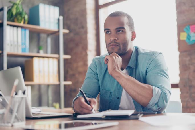 man thinking while using laptop and writing notes