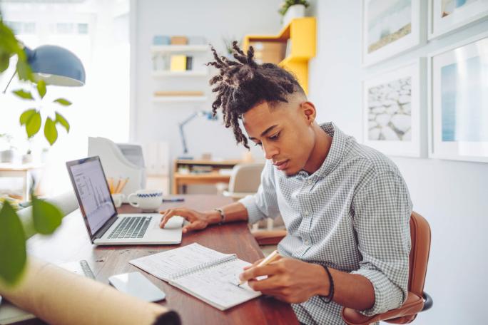 man using laptop and notebook at home