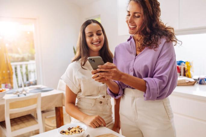 mother and daughter in the kitchen using smartphone