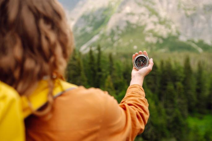 person holding a compass in their hand in the mountains