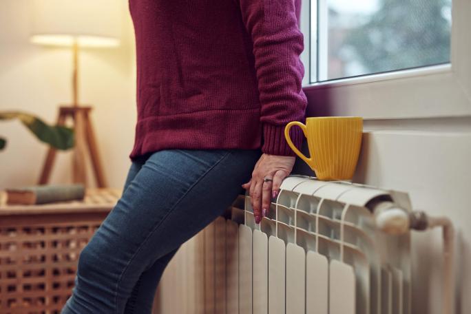 person leaning on a radiator for heat