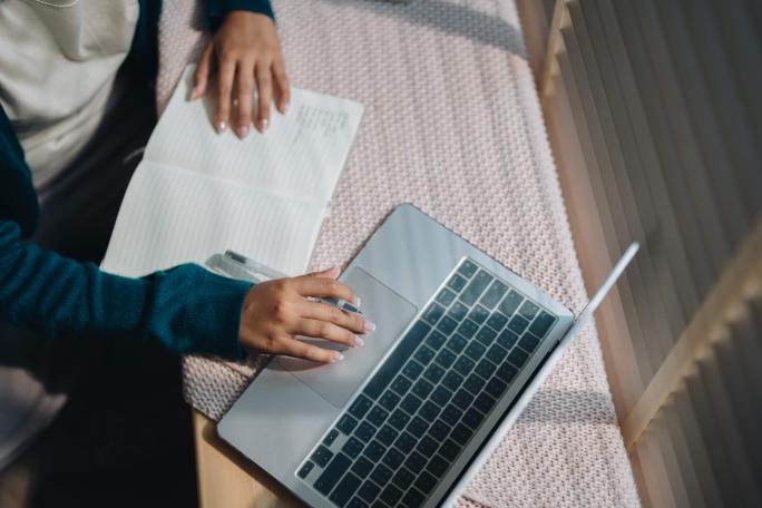 person using laptop and taking notes