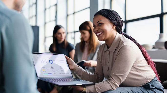 Colleagues discussing work on a laptop