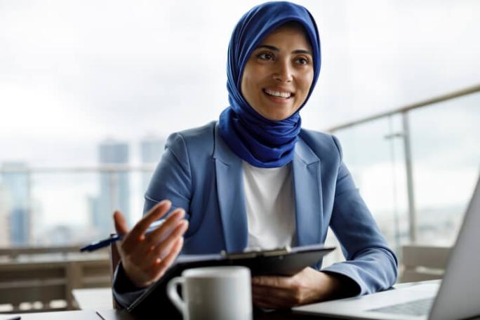 professional smiling woman sat on roof terrace with laptop