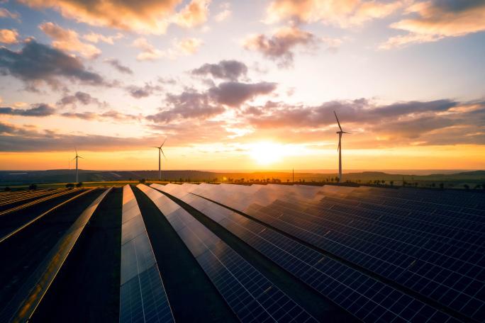 sunset view over solar panels with windmill turbines in the distance
