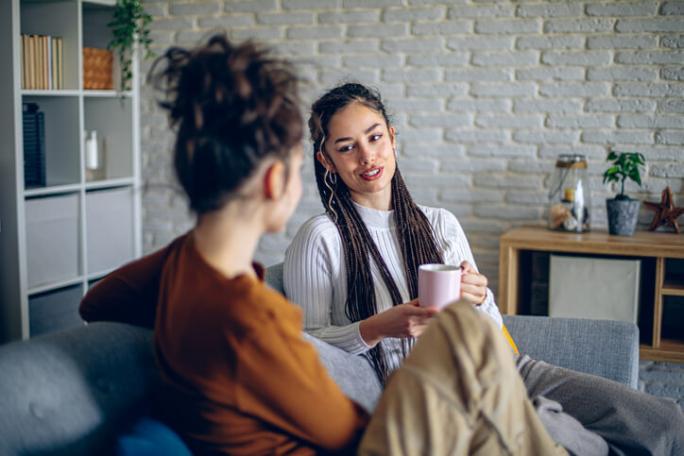 two friends sat on sofa having a chat