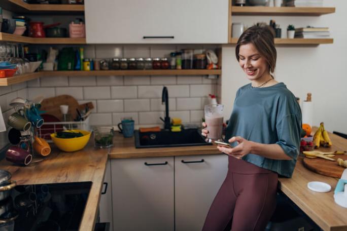 woman drinking protein shake in kitchen