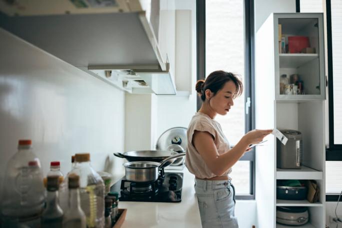 woman leaning against counter in kitchen reading mail