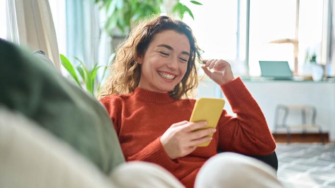 woman looking at phone while sat on sofa