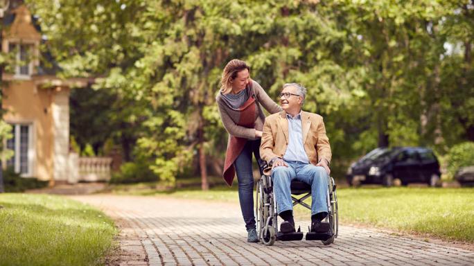 woman pushing elderly man in wheelchair