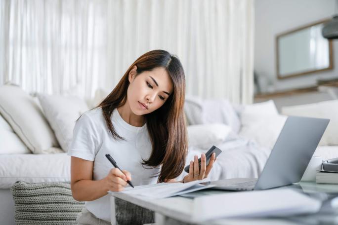 woman sitting on the floor by the sofa working on finances
