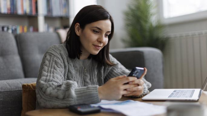 woman using her phone and laptop