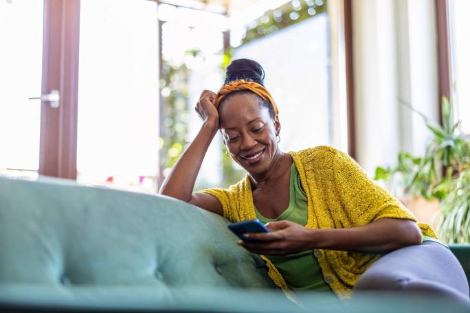 woman using her smartphone relaxing on the sofa