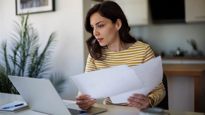 woman using laptop and papers to do her finances