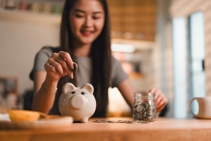 young woman putting coins in piggy bank