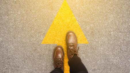 yellow-arrow-on-tarmac-with-person-in-brown-boots-standing-on-top.jpg