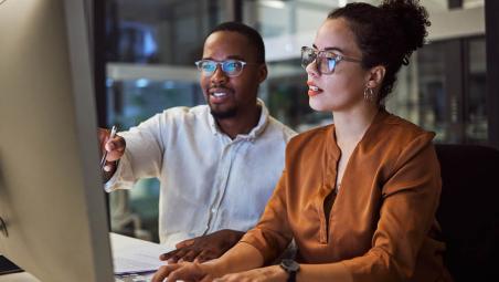A man and woman looking at figures on a computer screen
