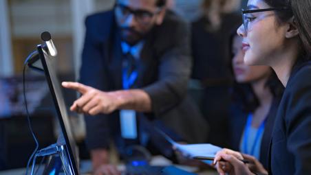 A man and two ladies looking at a computer screen