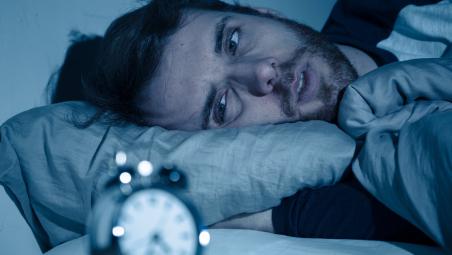Man trying to sleep but looking at clock 
