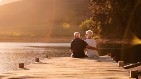 A retired couple sitting on the side of a lake