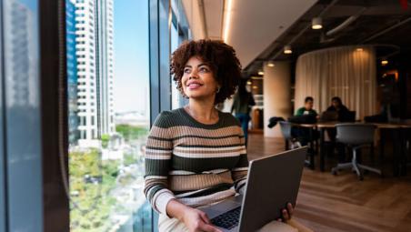 business woman in the office using laptop and looking out the window