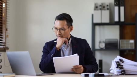 businessman thinking with paperwork and laptop in office