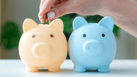 Yellow and blue piggy banks with a female hand