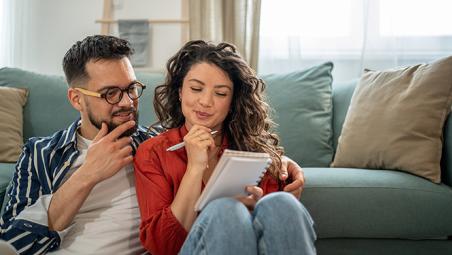 couple sat on the floor in their living room thinking and making notes