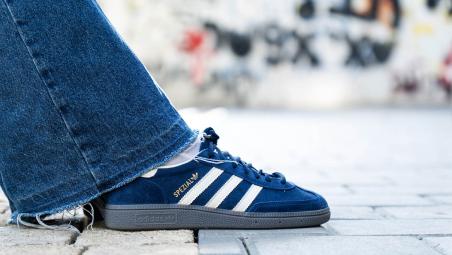 denim trouser leg and blue adidas trainer