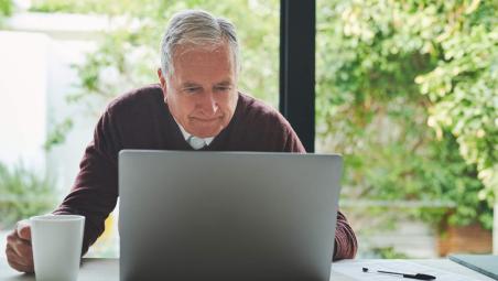 man using laptop and drinking coffee at home