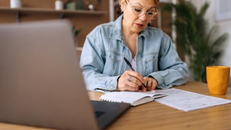 mature woman using laptop and taking notes