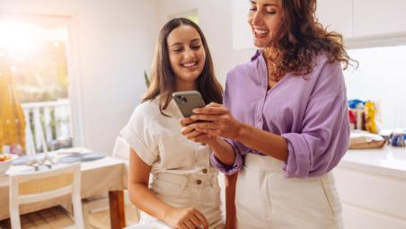 mother and daughter in the kitchen using smartphone