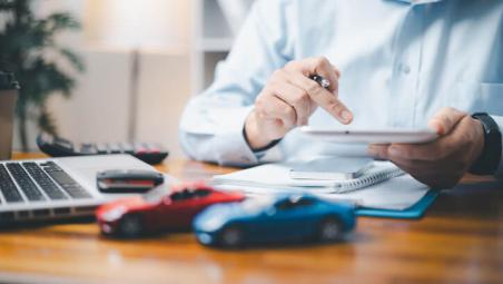 person sat behind office desk with laptop and toy cars