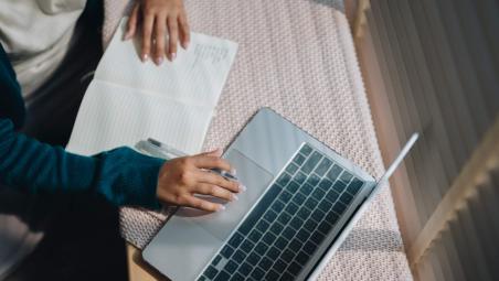 person using laptop and taking notes