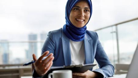 professional smiling woman sat on roof terrace with laptop