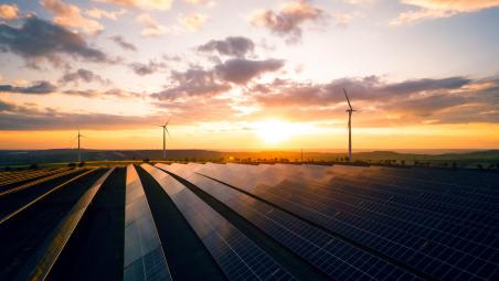 sunset view over solar panels with windmill turbines in the distance