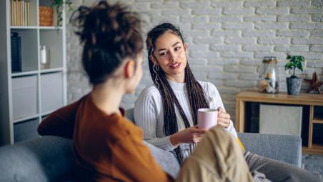 two friends sat on sofa having a chat